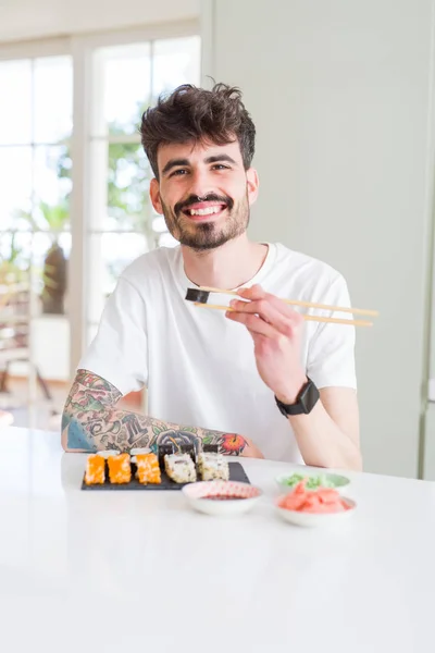 Young man eating sushi asian food using choopsticks