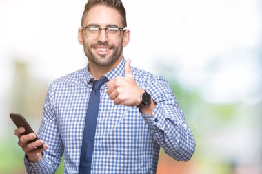 Ok işareti, başparmak ile parmak, mükemmel işareti yapıyor kocaman bir gülümseme ile izole arka plan üzerinde mutlu Smartphone kullanarak genç iş adamı