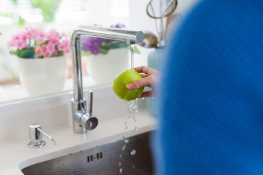 Genç kadın lavabo su kullanarak sebze ve meyve yıkama