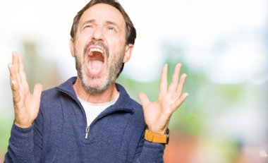 Orta yaş yakışıklı adam deli ve deli bağırarak ve agresif ifade ve silah kaldırdı bağırıyor bir kazak giyiyor. Hayal kırıklığı kavramı.