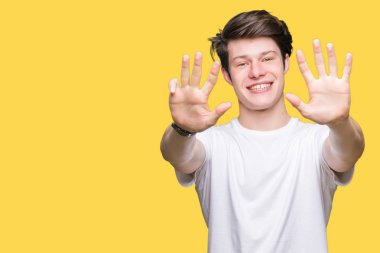 Yakışıklı delikanlı gösterilen ve parmakları ile işaret izole arka plan üzerinde rahat beyaz t-shirt giyen numara 9 kendinden emin ve mutlu gülümseyerek süre.