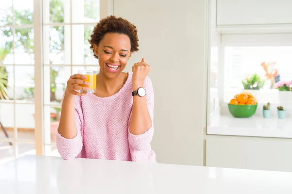 年轻的非洲裔美国妇女在家里喝橙汁尖叫自豪和庆祝胜利和成功非常兴奋 欢呼的情绪 — 图库照片