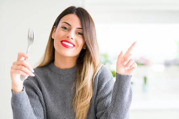 Joven Hermosa Mujer Sosteniendo Tenedor Plata Casa Muy Feliz Señalando —  Fotos de Stock