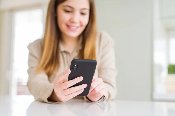 Primer plano de la mujer usando el teléfono inteligente y sonriendo confiado —  Fotos de Stock