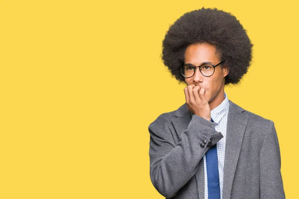 Young african american business man with afro hair wearing glasses looking stressed and nervous with hands on mouth biting nails. Anxiety problem.