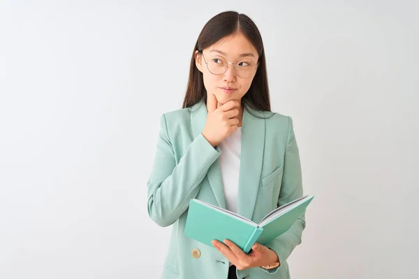 年轻的中国留学生妇女戴眼镜看书过偏偏白背景严肃面对思考问题 思想很困惑 — 图库照片