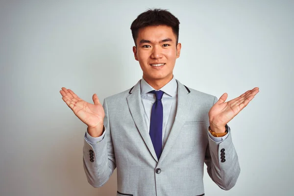 アジアの中国人ビジネスマンは 孤立した黄色の背景の上に立ってスーツとネクタイを着用し 腕と手を上げて混乱した表情を浮かべた 疑いの概念 — ストック写真