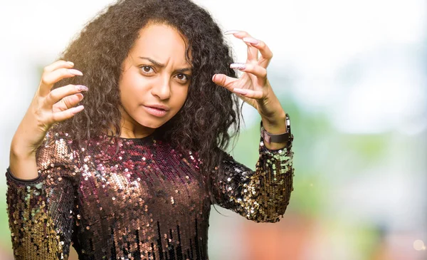 Young beautiful girl with curly hair wearing night party dress Shouting frustrated with rage, hands trying to strangle, yelling mad