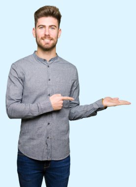 Hayret ve el ile sunulması ve parmak ile işaret ederken kameraya gülümseyen genç yakışıklı iş casual adam.