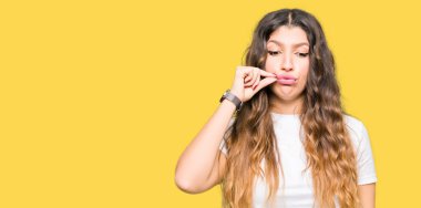 Casual beyaz t-shirt ağız ve dudaklar giyen genç güzel kadın olarak ZIP parmak ile kapatın. Gizli ve sessiz, tabu söz