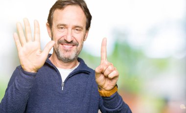 Gösterilen ve parmakları ile işaret Kazak giyen orta yaş yakışıklı adam kendinden emin ve mutlu gülümseyerek süre 6 numara.