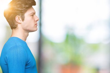 İzole arka tarafına, seyir üzerinde mavi kazak giyen genç yakışıklı adam sakin ol kendine güvenen gülümseme ile doğal yüz pozuyla profili.