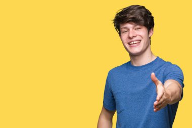 Tebrik ve konuksever dost sunan karşılıklı gülümseyen izole arka plan üzerinde mavi t-shirt giyen genç yakışıklı adam. Başarılı iş.