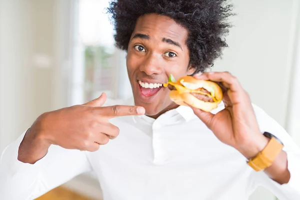 Hombre Afroamericano Hambriento Comiendo Hamburguesa Para Almuerzo Muy Feliz Señalando — Foto de Stock