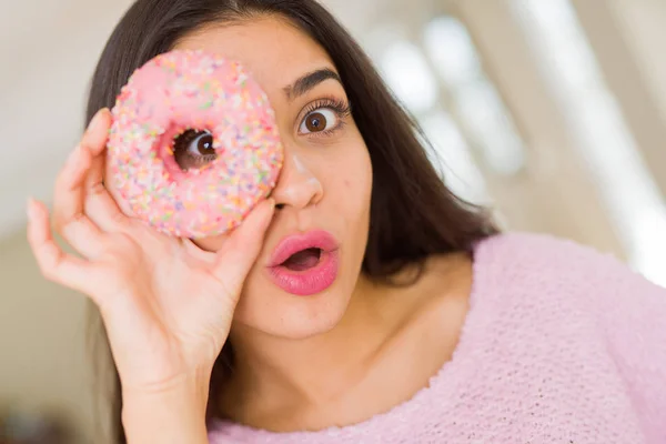 Belle jeune femme regardant à travers beignet rose sur l'oeil avec — Photo