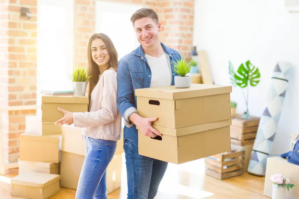 Hermosa pareja joven sonriendo en amor sosteniendo cajas de cartón , — Foto de Stock