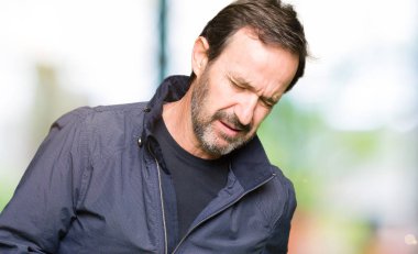 Orta yaş yakışıklı adam çünkü mide üzerinde el ile bir ceket giyen mide bulantısı, ağrılı hastalık hasta hissediyor. Ağrısı kavramı.
