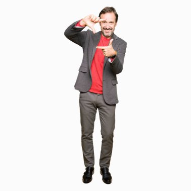 Orta yaş yakışıklı iş adamı elle yapma çerçeve ve parmakları ile mutlu yüz gülümseyerek. Yaratıcılık ve Fotoğrafçılık kavramı.