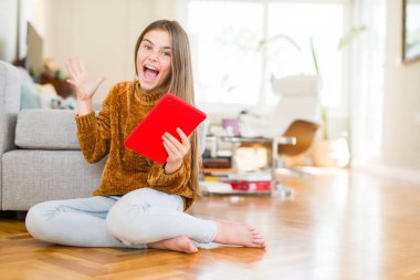 Güzel genç kız çocuk çok mutlu ve heyecanlı katta oturan dijital touchpad tablet kullanarak, büyük bir gülümseme ile çığlık zafer kutlayan kazanan ifade ve ellerini kaldırdı
