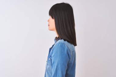 Denim gömlek ve izole beyaz arka plan üzerinde kırmızı çizgili t-shirt giyen Çinli kadın yan bakarak, kendine güvenen gülümseme ile doğal yüz ile profil poz dinlenmek.