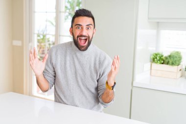 Yakışıklı İspanyol adam evde rahat kazak giyen deli kutluyor ve başarı için hayran silah kaldırdı ve açık gözleri heyecanlı çığlık. Kazanan kavramı