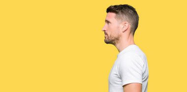 Yakışıklı erkek tarafına, seyir casual beyaz t-shirt giyen dinlenmek doğal yüz emin gülümseme ile pozuyla profili.