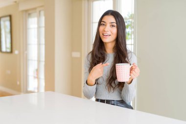 Bir fincan kahve içen genç kadın el ve parmakla işaret etmekten çok mutlu