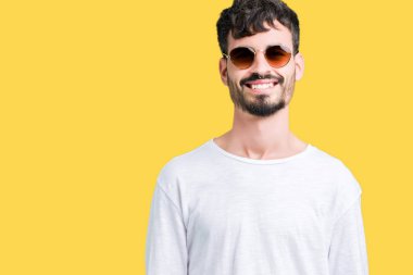 Genç yakışıklı adam yüzünde mutlu ve güzel bir gülümseme ile izole arka plan üzerinde güneş gözlüğü takıyor. Şanslı kişi.