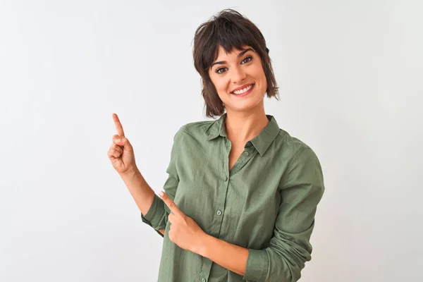 年轻的美丽女人穿着绿色休闲衬衫站在孤立的白色背景微笑 看着相机指着两只手和手指的一侧 — 图库照片