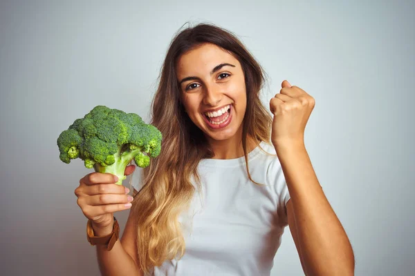 Ung Vacker Kvinna Äter Broccoli Över Grå Isolerad Bakgrund Skrikande — Stockfoto
