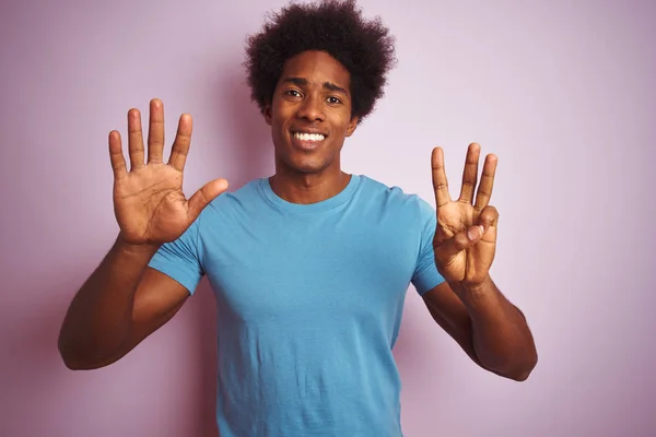 非洲裔美国男子与非洲裔头发穿着蓝色T恤站在孤立的粉红色背景显示和指向手指8 同时微笑自信和快乐 — 图库照片