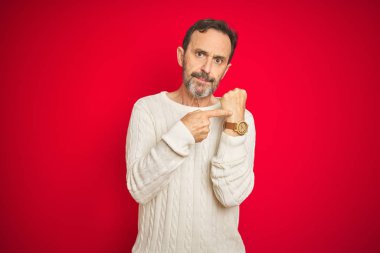 Izole kırmızı arka plan üzerinde gri saçlı yakışıklı orta yaş yaşlı adam Acele zaman izlemek için işaret, sabırsızlık, rahat ifade ile kameraya bakarak