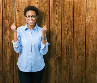 İzole arka plan üzerinde genç güzel Afrikalı Amerikan iş kadını şaşırttı ve silah kaldırdı ve açık gözleri ile başarı için şaşırdı kutluyor. Kazanan kavramı.