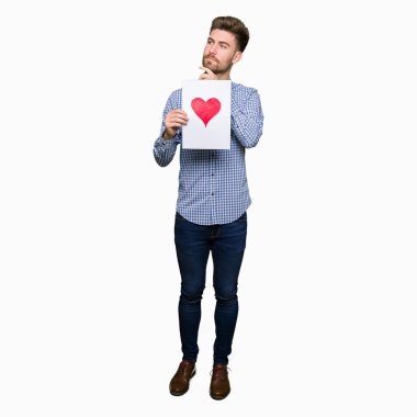 Kırmızı kalp ciddi bir yüz düşünce hakkında soru, çok karışık bir fikir ile kağıt tutan genç yakışıklı adam