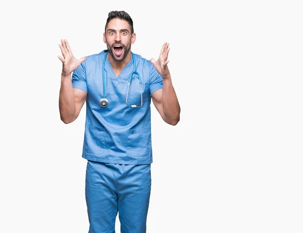英俊的年轻医生外科医生男子在孤立的背景庆祝疯狂和惊讶的成功与手臂抬起和睁开眼睛尖叫兴奋 优胜者概念 — 图库照片
