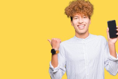 Genç yakışıklı adam akıllı telefon ekranı gösteren işaret ve mutlu yüzü gülümseyerek yan başparmak ile gösteren