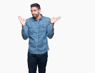 İzole arka plan clueless ve şaşkın bir ifadeyle kollar ve eller kaldırdı genç yakışıklı adam. Şüphe kavramı.