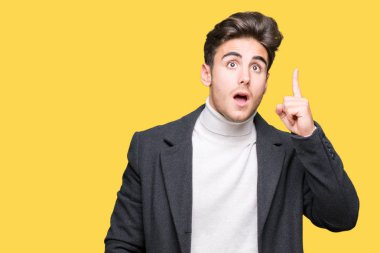 Genç zarif adam başarılı fikirle izole arka plan işaret parmağı üzerinde kış palto giyiyor. Çıktıktan ve mutlu. Bir numara.