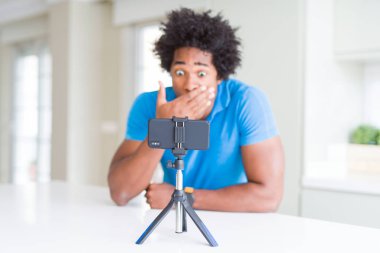 Afro-Amerikan adam hata için utanç ile şok el ile akıllı telefon kapağı ağız kullanarak web kamerası ile online arama yapıyor, korku ifadesi, sessizlik, gizli kavram korkmuş