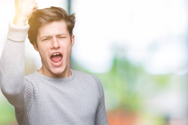 Üzerinde kış kazak giyen genç yakışıklı adam arka plan kızgın izole ve kızgın yetiştirme hayal kırıklığı ve öfke ile bağırarak süre öfkeli yumruk. Öfke ve agresif kavramı.