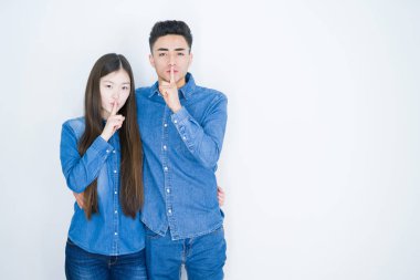 Beyaz izole arka plan üzerinde güzel genç asyalı çift dudaklarında parmak ile sessiz olmak isteyen. Sessizlik ve gizli kavram.