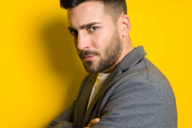 Genç yakışıklı adam possing ve modelleme sarı izole bac üzerinde