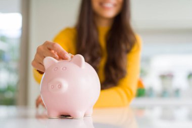 Kadın gibi Piggy banka içinde bir sikke koyarak gülümseyen yakın