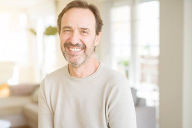 Evde kameraya bakarak gülümseyen yakışıklı orta yaş erkek