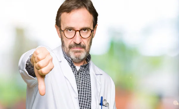 中年医生穿着医疗外套 看上去不开心 表现出拒绝和负面的大拇指向下的姿态 错误的表达 — 图库照片