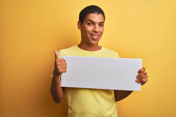 Homem Árabe Bonito Jovem Segurando Banner Sobre Fundo Amarelo Isolado — Fotografia de Stock