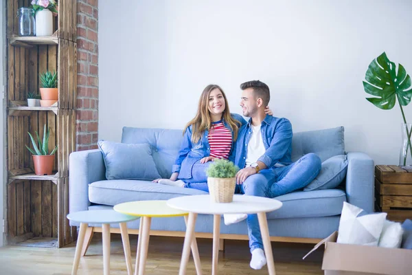 Junges schönes Paar sitzt und umarmt auf dem Sofa bei neuen ap — Stockfoto