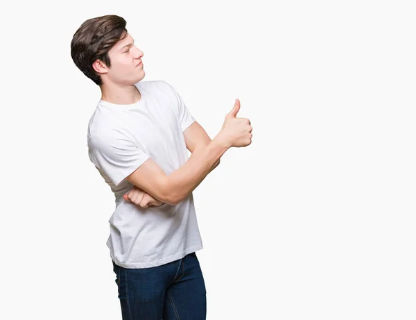 年轻英俊的男人穿着休闲白色 T恤在孤立的背景看着骄傲 微笑着做大拇指的手势到一边 — 图库照片