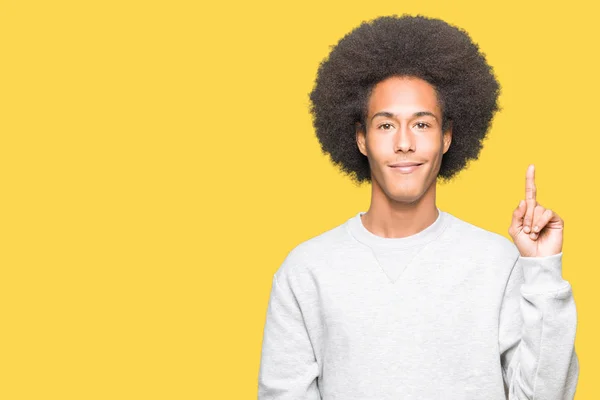 スポーティなスウェット シャツ表示と自信を持って 幸せな笑みを浮かべて 指番号のいずれかで上向きを身に着けているアフロの髪の若いアフリカ系アメリカ人 — ストック写真