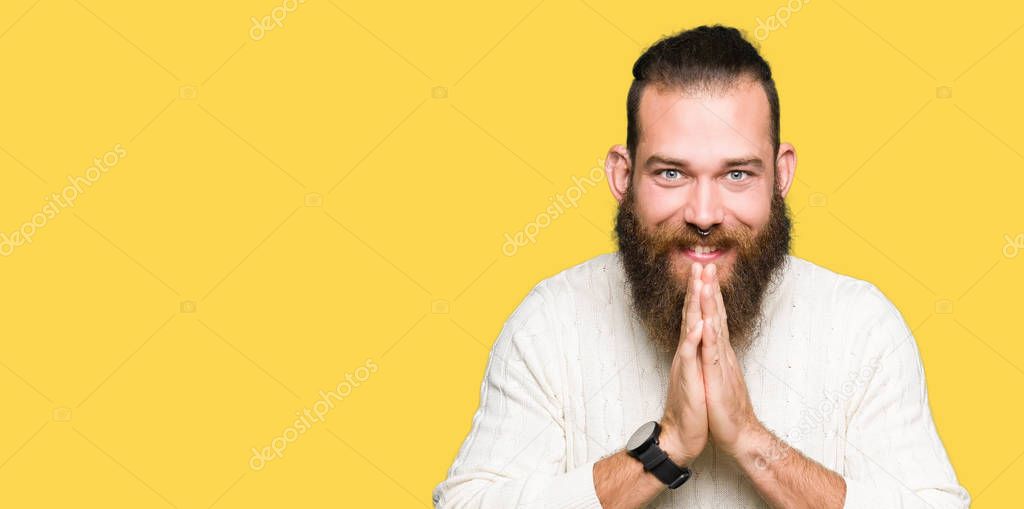 Young hipster man wearing winter sweater praying with hands together asking for forgiveness smiling confident.